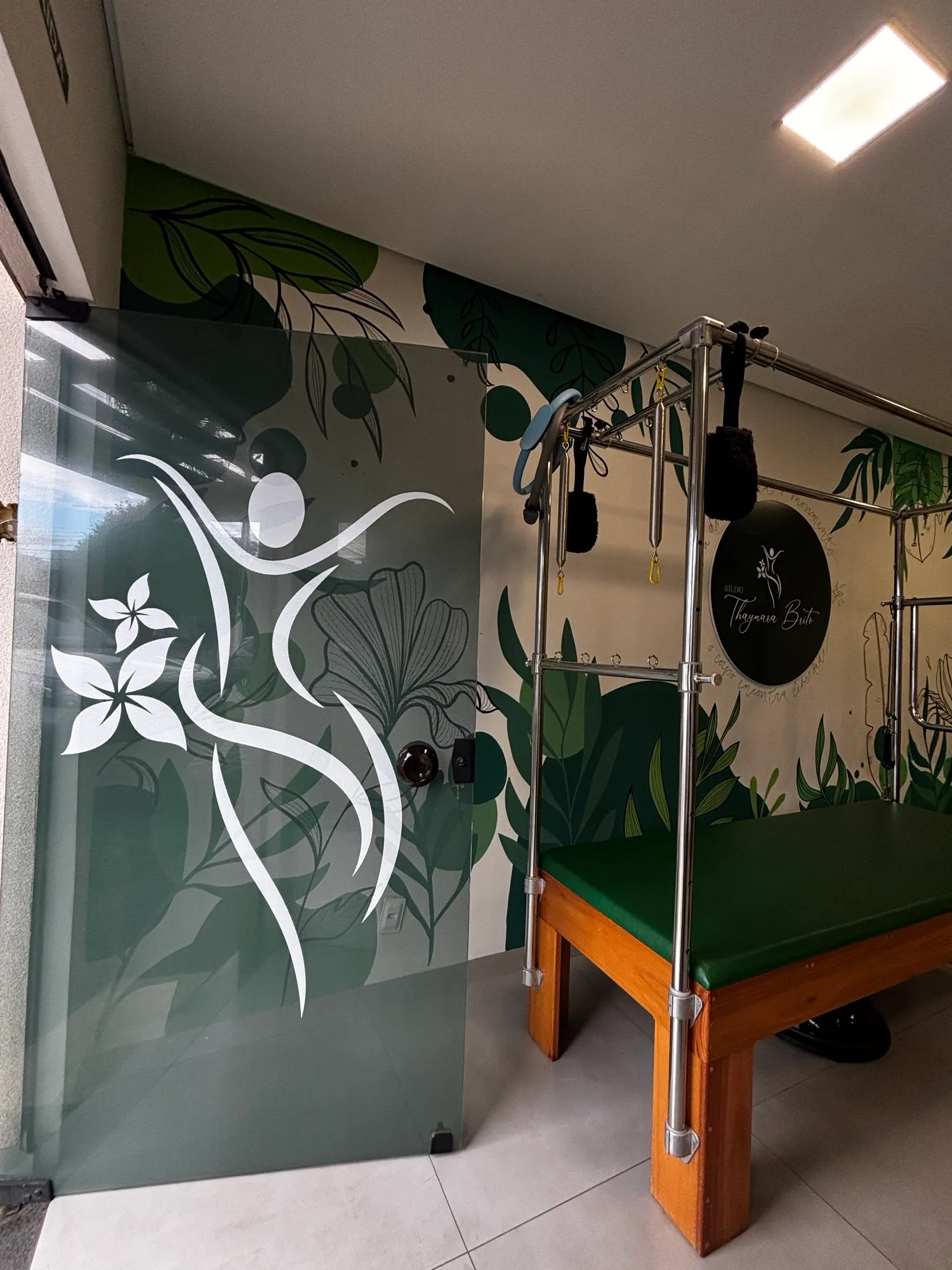 Entrada do studio com a figura do logo no vidro e o Cadillac de Pilates ao fundo